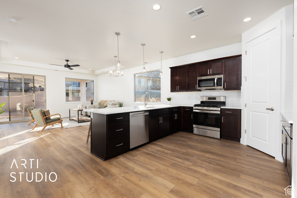 Kitchen featuring a healthy amount of sunlight, stainless steel appliances, decorative light fixtures, and kitchen peninsula