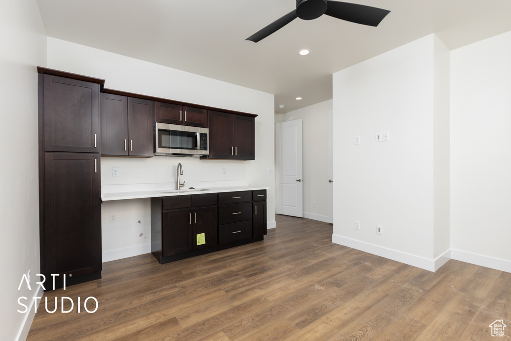 Kitchen with ceiling fan, dark brown cabinets, sink, and hardwood / wood-style floors