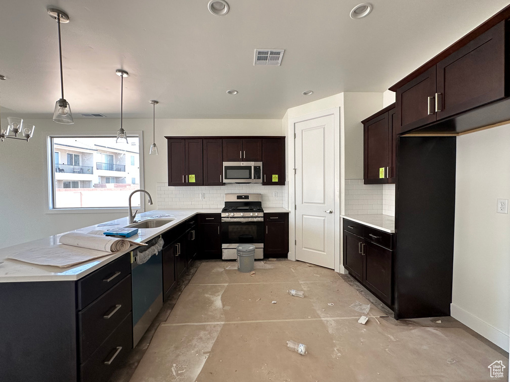 Kitchen with stainless steel appliances, sink, pendant lighting, decorative backsplash, and dark brown cabinetry