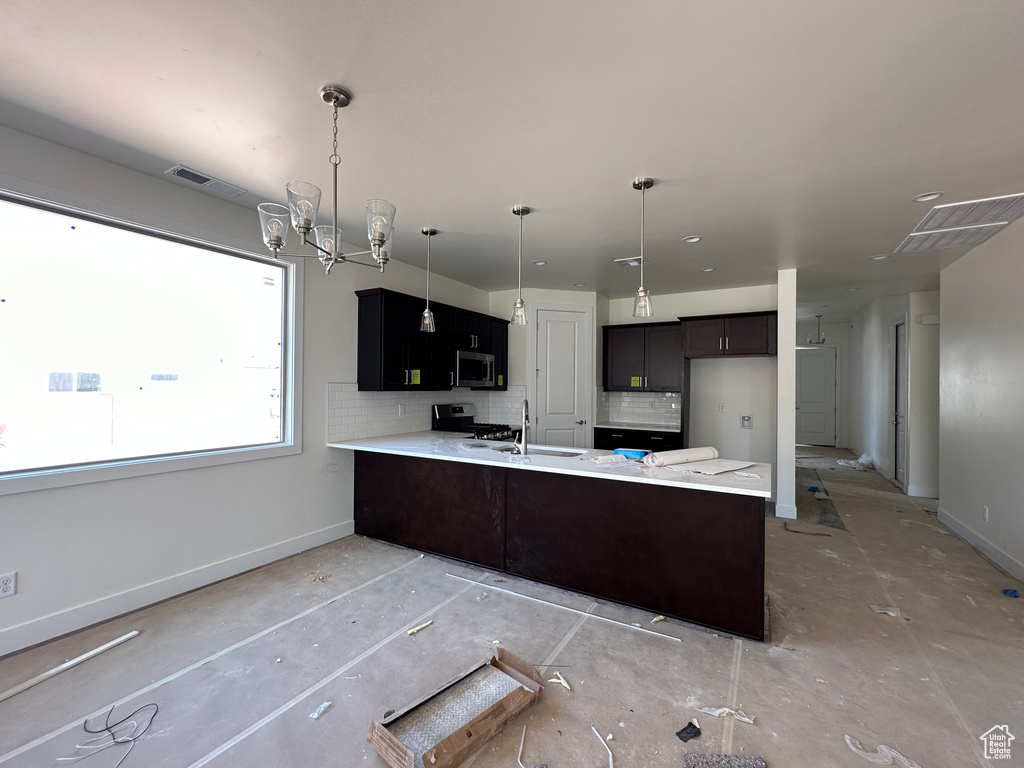 Kitchen with tasteful backsplash, kitchen peninsula, an inviting chandelier, sink, and appliances with stainless steel finishes