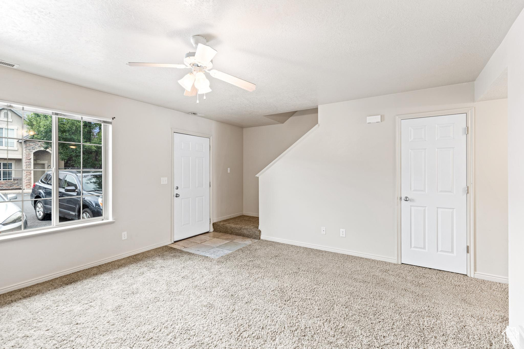 Carpeted spare room featuring ceiling fan