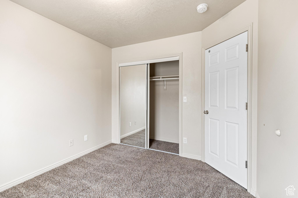 Unfurnished bedroom featuring a closet and light colored carpet