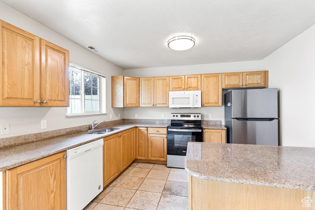 Kitchen featuring light brown cabinets, sink, stainless steel appliances, and light tile patterned floors