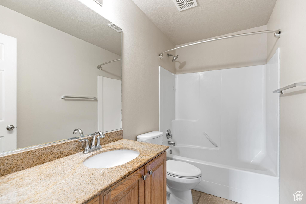 Full bathroom with tile patterned flooring, a textured ceiling, toilet, shower / bathtub combination, and vanity