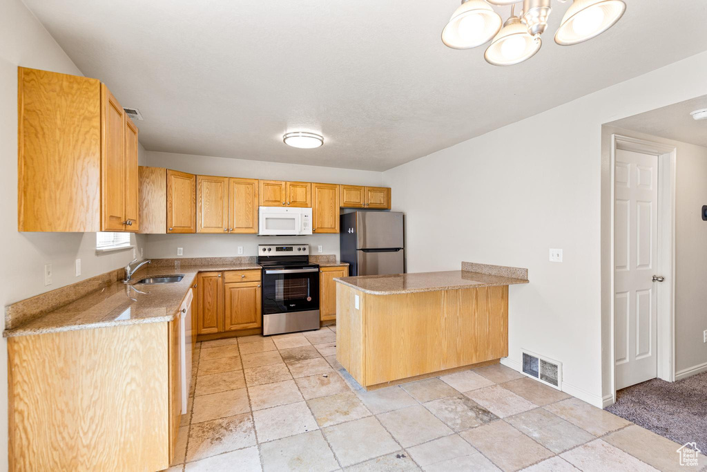 Kitchen with light stone counters, appliances with stainless steel finishes, light tile patterned floors, and kitchen peninsula