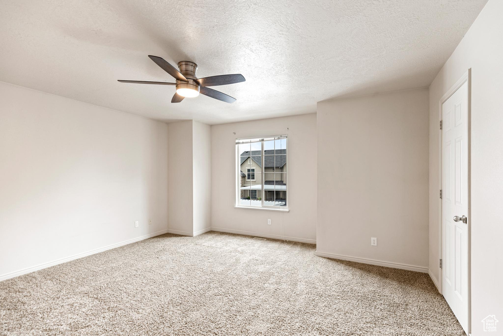 Carpeted empty room with a textured ceiling and ceiling fan