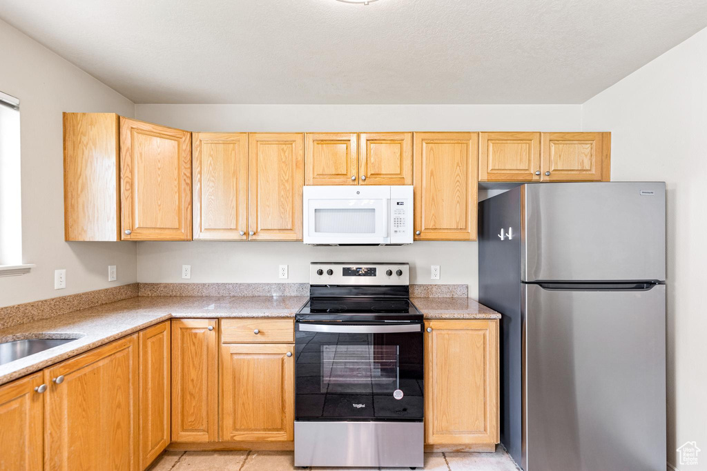 Kitchen featuring light brown cabinetry, light tile patterned floors, and stainless steel appliances