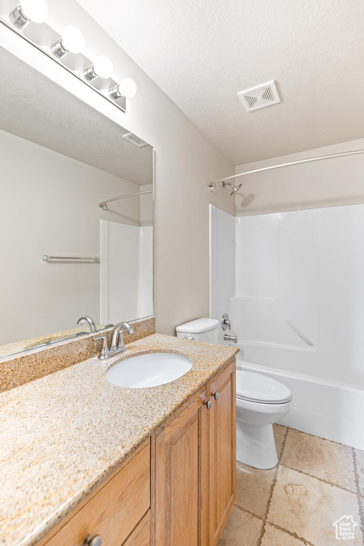 Full bathroom featuring shower / bathtub combination, tile patterned flooring, a textured ceiling, toilet, and vanity