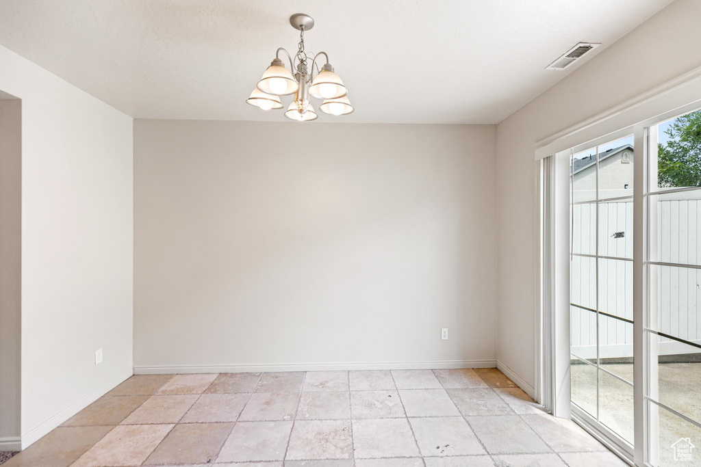 Unfurnished room featuring an inviting chandelier and light tile patterned floors