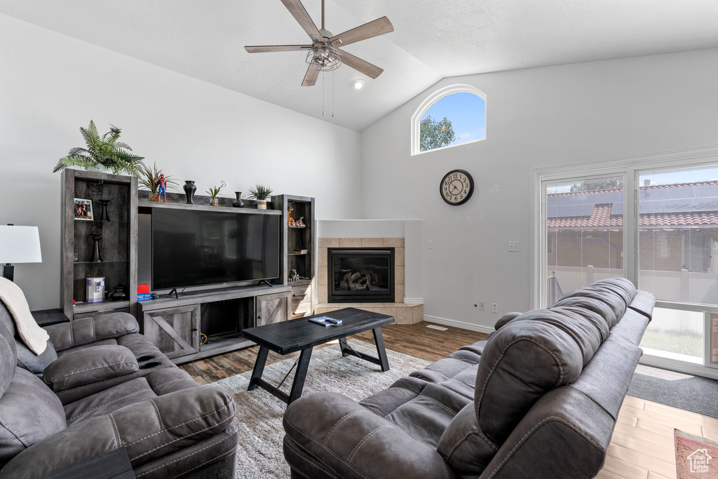 Living room with a tile fireplace, hardwood / wood-style floors, high vaulted ceiling, and ceiling fan