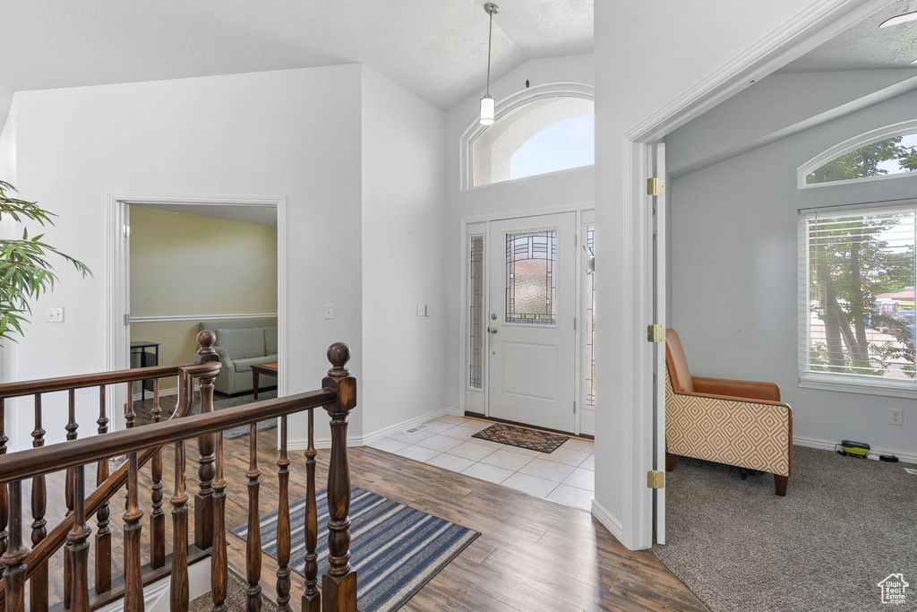 Foyer entrance with light hardwood / wood-style flooring and high vaulted ceiling