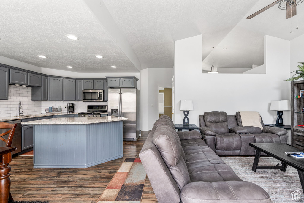 Kitchen with gray cabinets, appliances with stainless steel finishes, decorative backsplash, and dark hardwood / wood-style floors