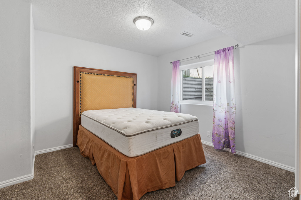 Carpeted bedroom featuring a textured ceiling