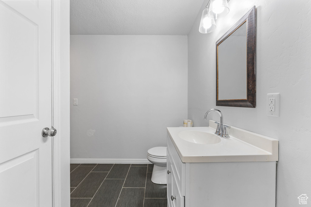 Bathroom with vanity, toilet, a textured ceiling, and tile patterned flooring