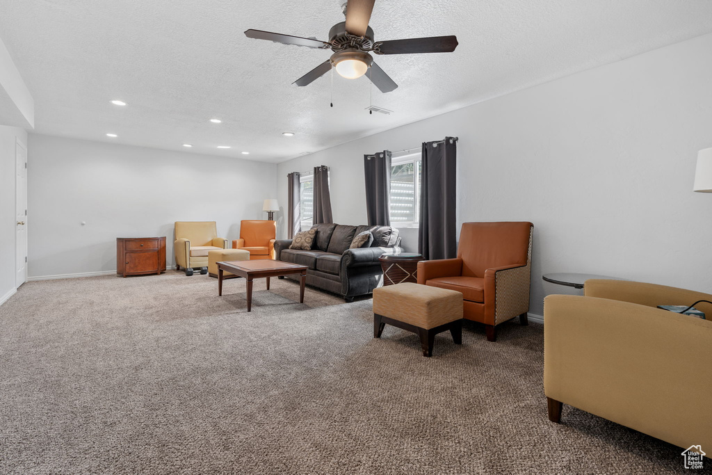 Carpeted living room with a textured ceiling and ceiling fan