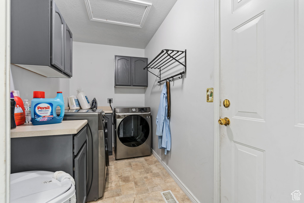 Washroom with light tile patterned flooring, cabinets, and washing machine and clothes dryer