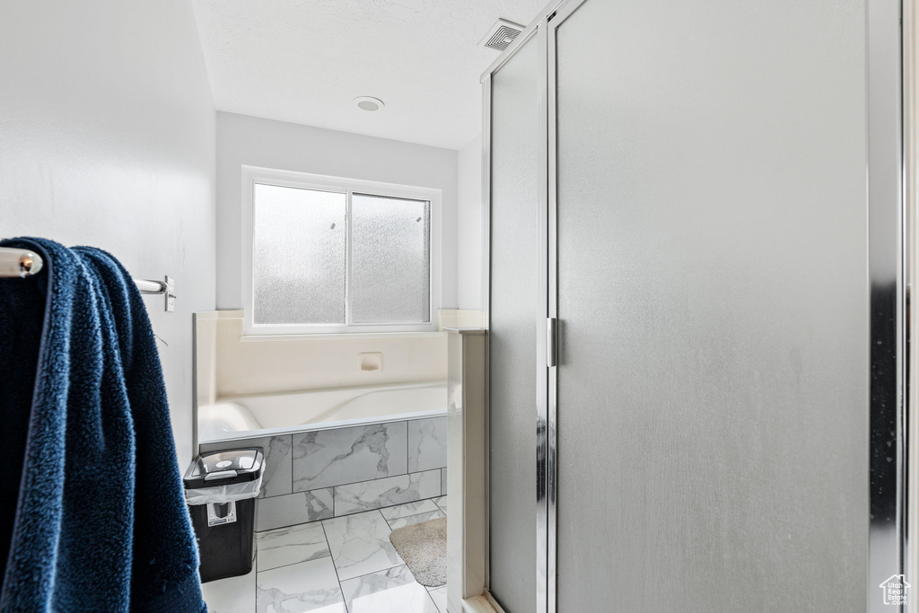 Bathroom featuring independent shower and bath and tile patterned flooring