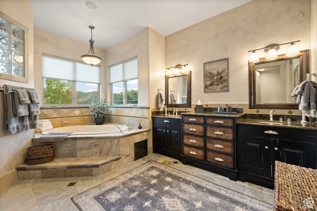 Bathroom featuring double vanity, tile patterned flooring, and tiled bath