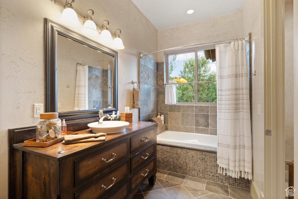 Bathroom with vanity, tile patterned floors, and a relaxing tiled tub