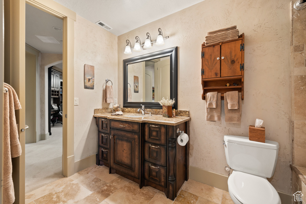 Bathroom featuring vanity, toilet, and tile patterned flooring