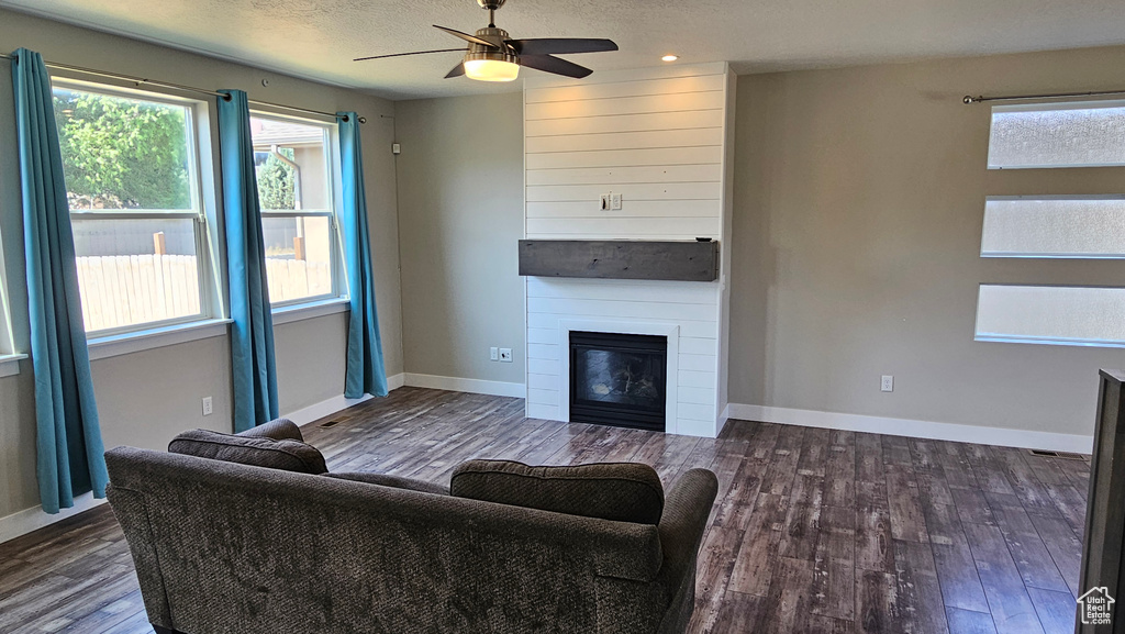 Living room featuring a large fireplace, a wealth of natural light, ceiling fan, and hardwood / wood-style floors