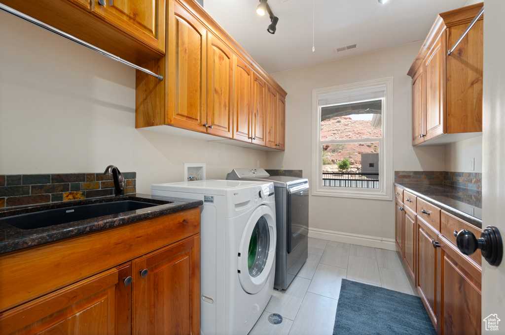 Laundry area featuring washer and clothes dryer, rail lighting, sink, cabinets, and light tile patterned floors