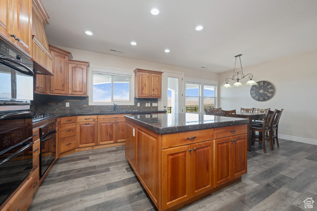 Kitchen with a wealth of natural light, wood-type flooring, decorative backsplash, and a kitchen island