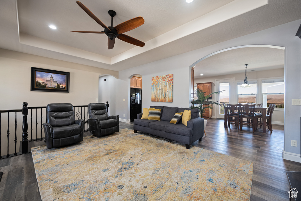 Living room featuring ceiling fan, a raised ceiling, and hardwood / wood-style floors