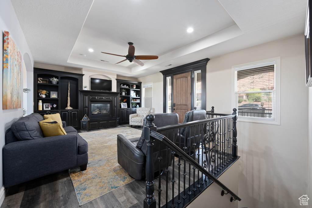 Living room featuring hardwood / wood-style floors, ceiling fan, and a raised ceiling