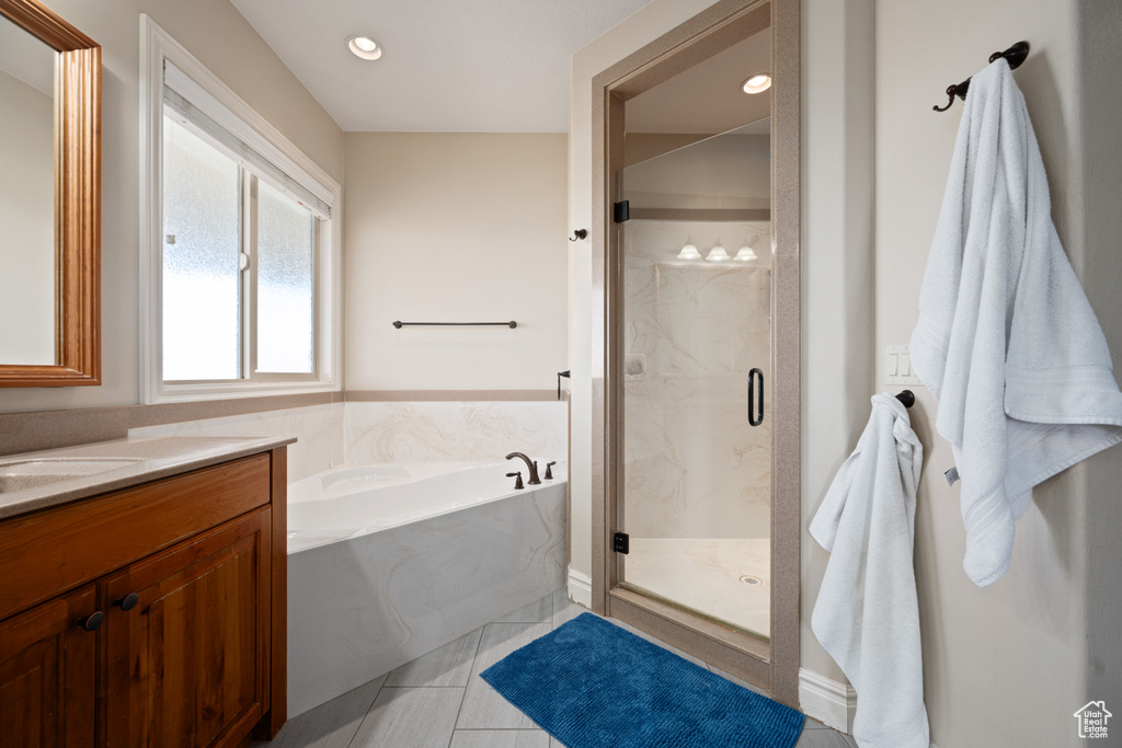 Bathroom featuring plus walk in shower, vanity, and tile patterned floors