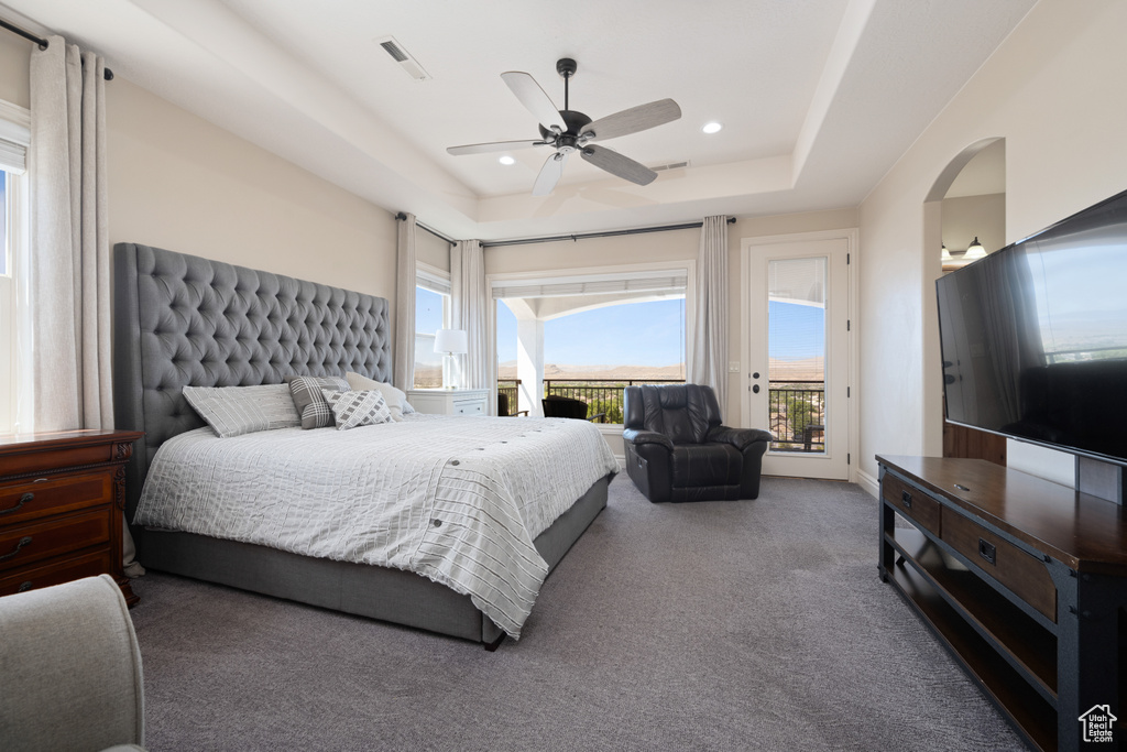 Bedroom with access to outside, ceiling fan, a raised ceiling, and carpet flooring