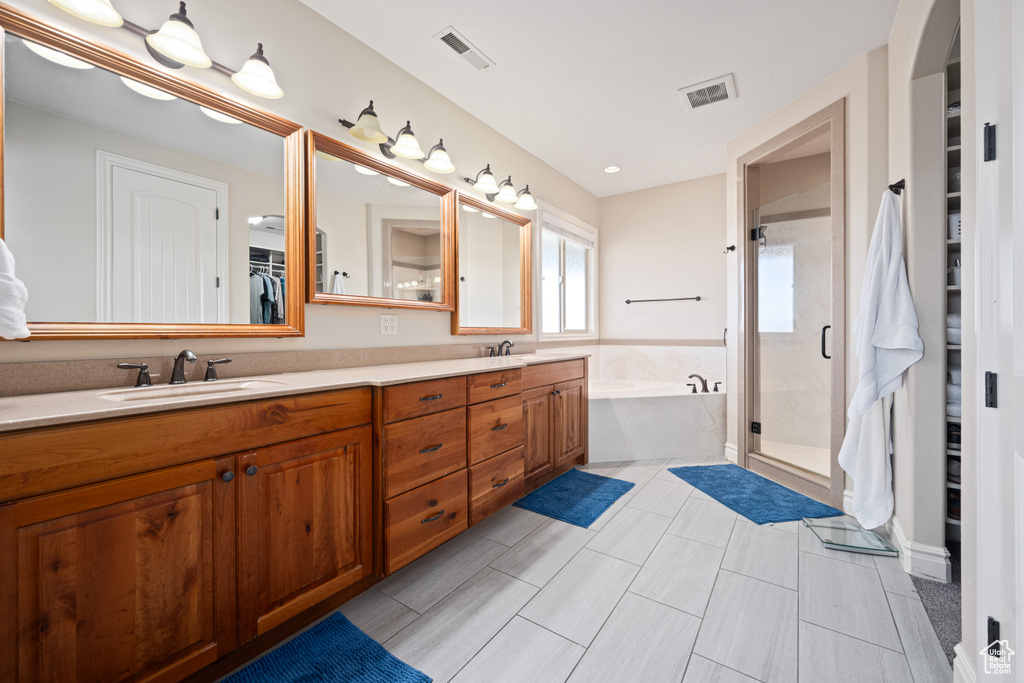 Bathroom with double vanity, plus walk in shower, and tile patterned floors