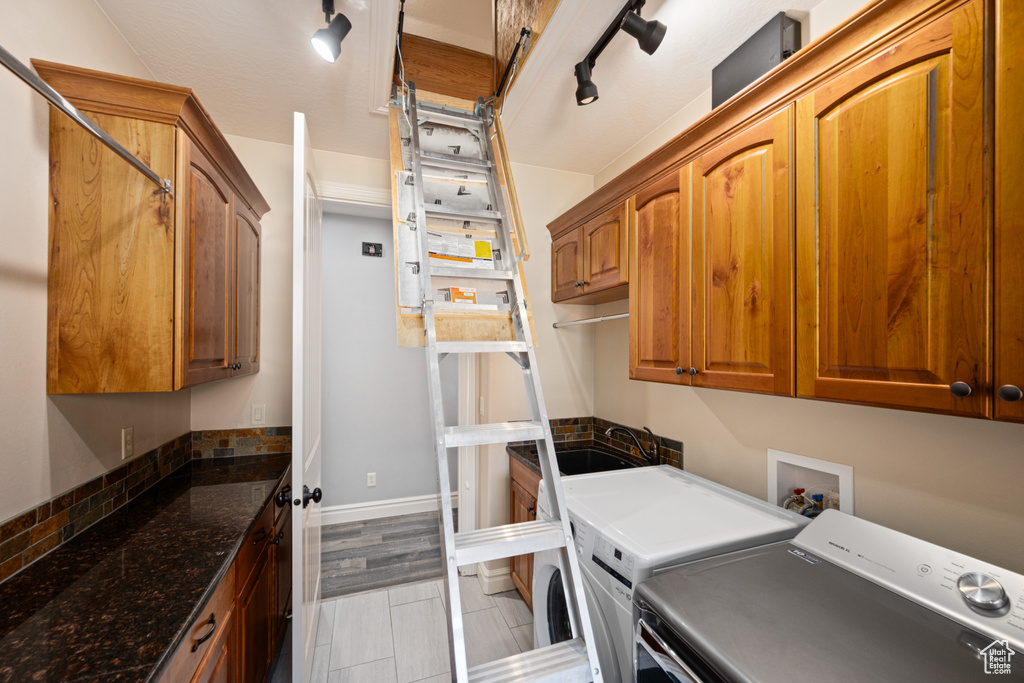 Washroom featuring independent washer and dryer, sink, rail lighting, and cabinets