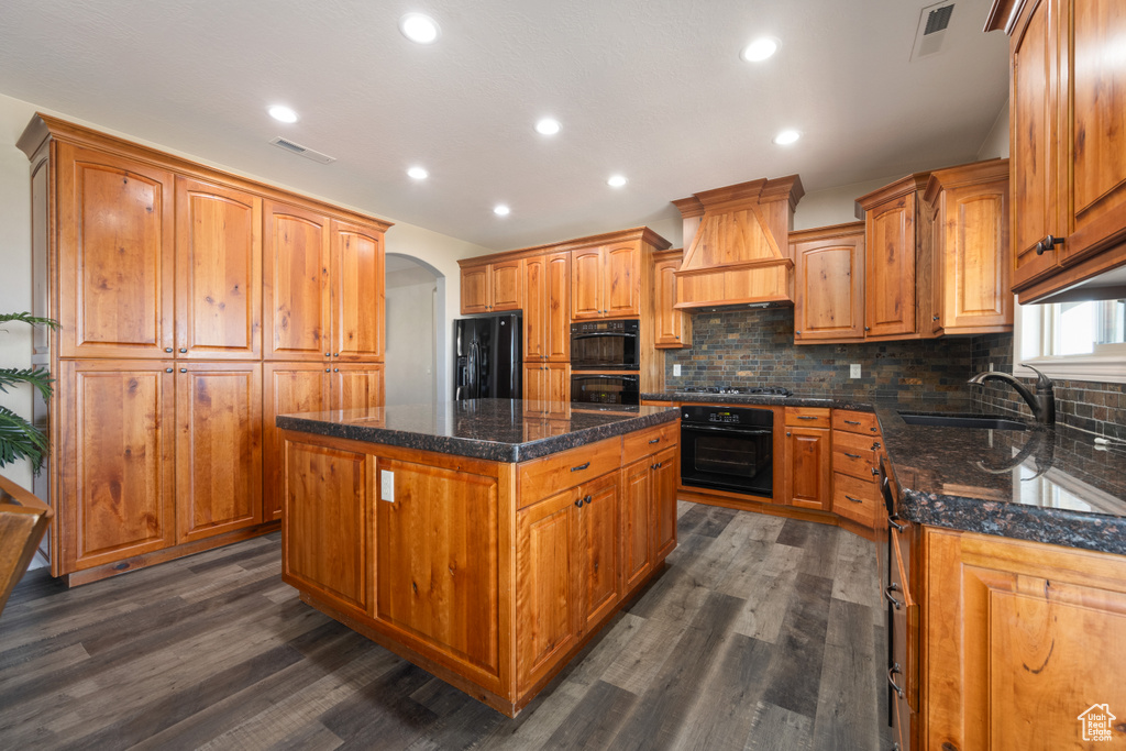 Kitchen with dark wood-type flooring, premium range hood, and a center island