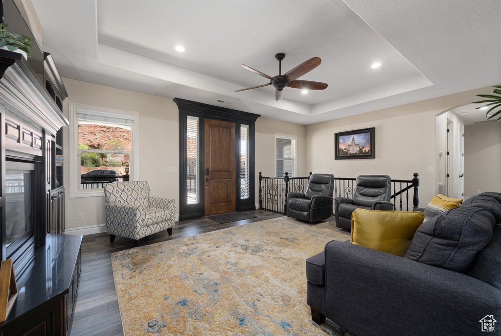 Living room featuring ceiling fan, dark hardwood / wood-style floors, and a tray ceiling