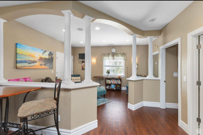 Kitchen featuring decorative columns, dark hardwood / wood-style flooring, a kitchen bar, and kitchen peninsula