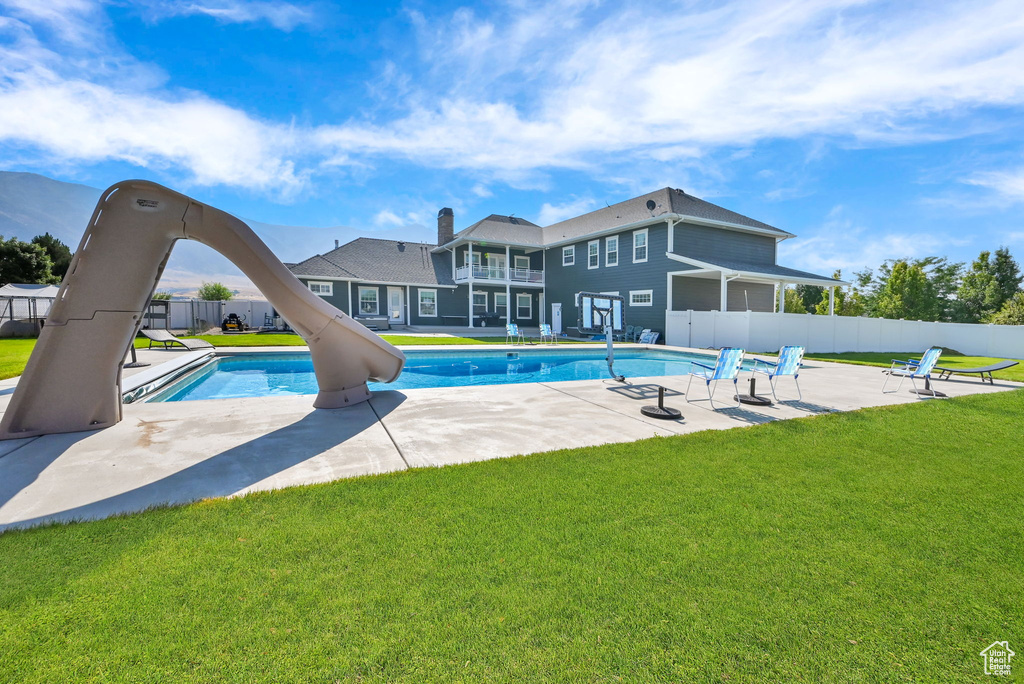 View of pool with a patio, a water slide, and a lawn