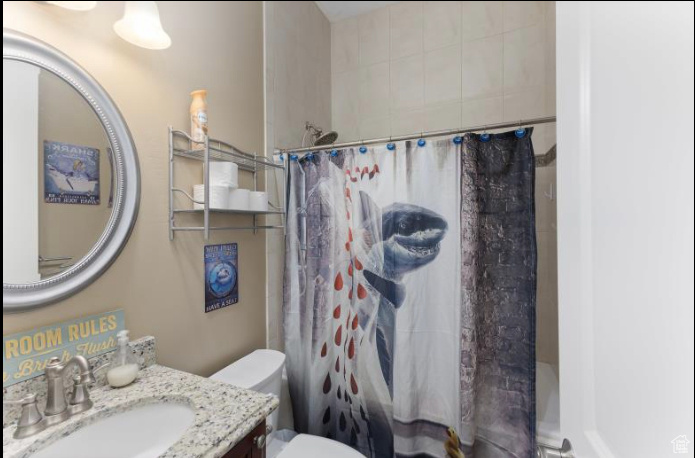 Full bathroom with toilet, shower / bath combo with shower curtain, and vanity