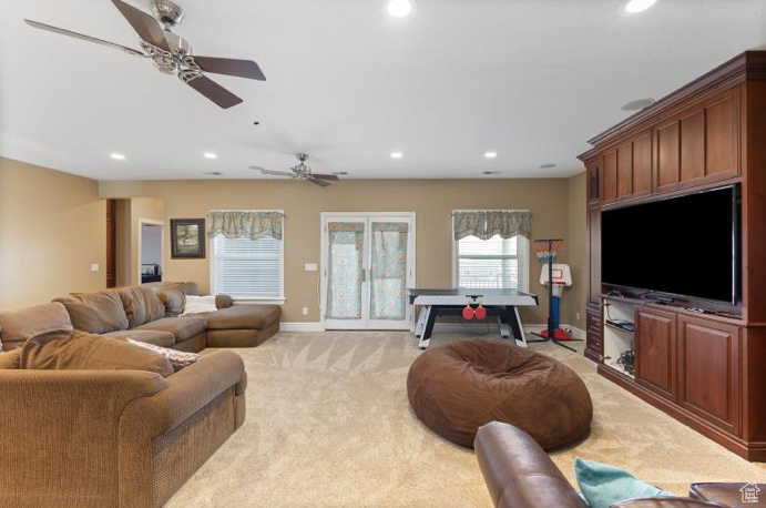 Carpeted living room featuring french doors and ceiling fan