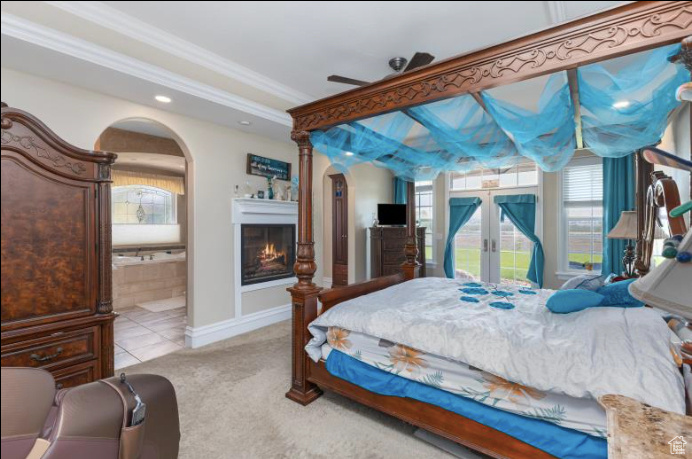 Bedroom featuring french doors, light colored carpet, and ensuite bathroom