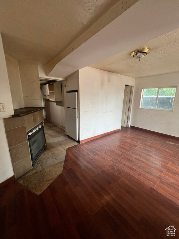 Unfurnished living room featuring a tile fireplace, light wood-type flooring, and a textured ceiling