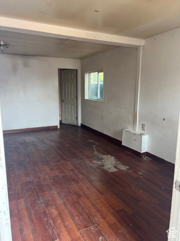 Unfurnished room with beam ceiling and hardwood / wood-style floors