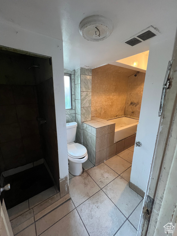 Bathroom featuring tile walls, tile patterned floors, plus walk in shower, and toilet