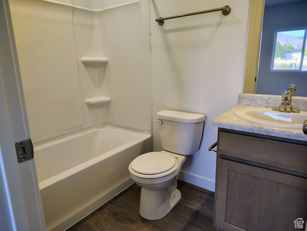 Full bathroom with wood-type flooring, vanity, bathing tub / shower combination, and toilet