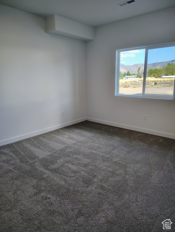 Unfurnished room featuring dark carpet and a mountain view