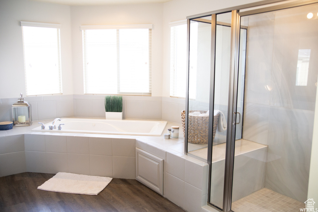 Bathroom featuring shower with separate bathtub, hardwood / wood-style flooring, and a healthy amount of sunlight