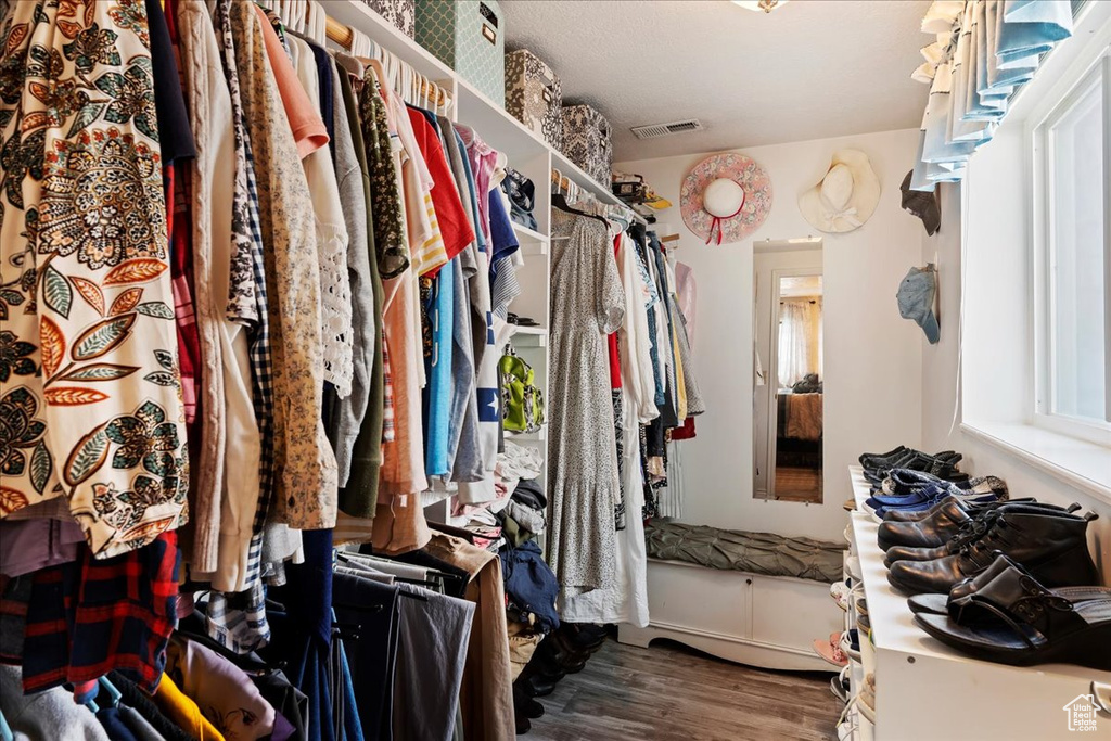 Walk in closet with hardwood / wood-style floors