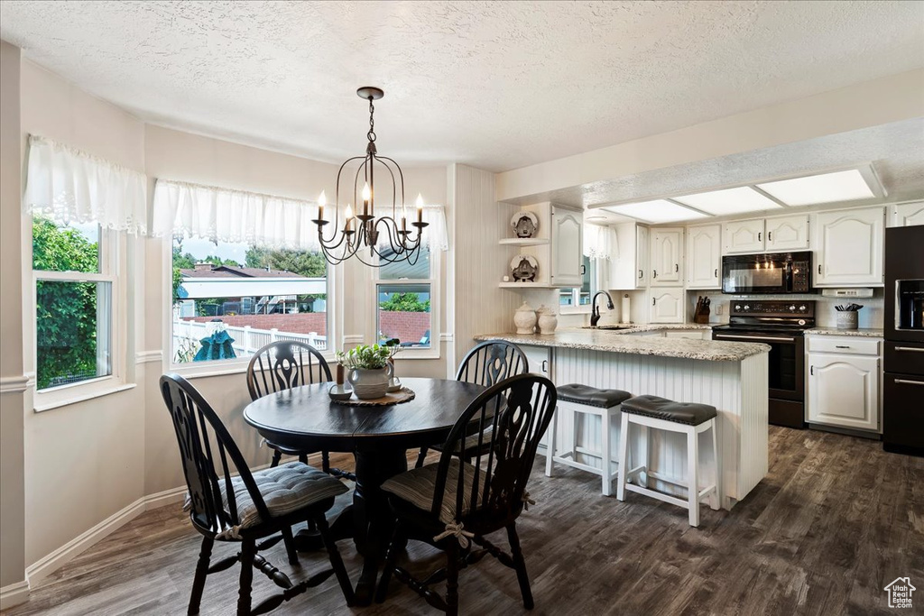 Dining room featuring sink, an inviting chandelier, a textured ceiling, and dark hardwood / wood-style floors