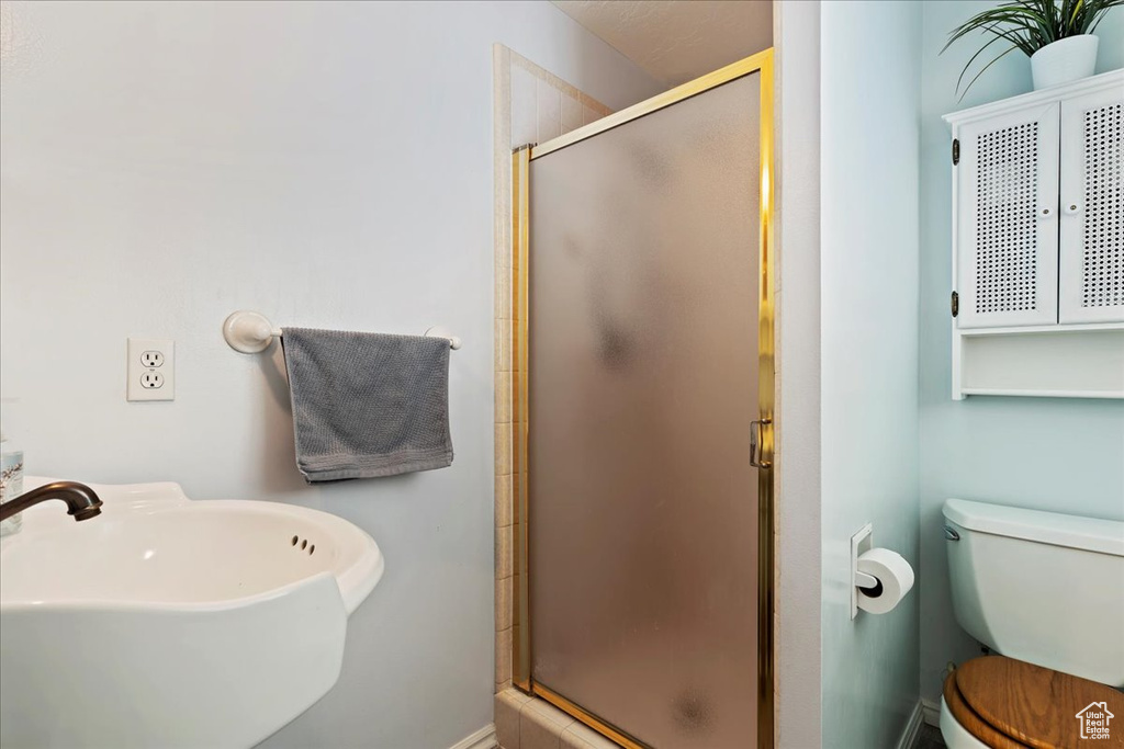 Bathroom featuring toilet, sink, and an enclosed shower