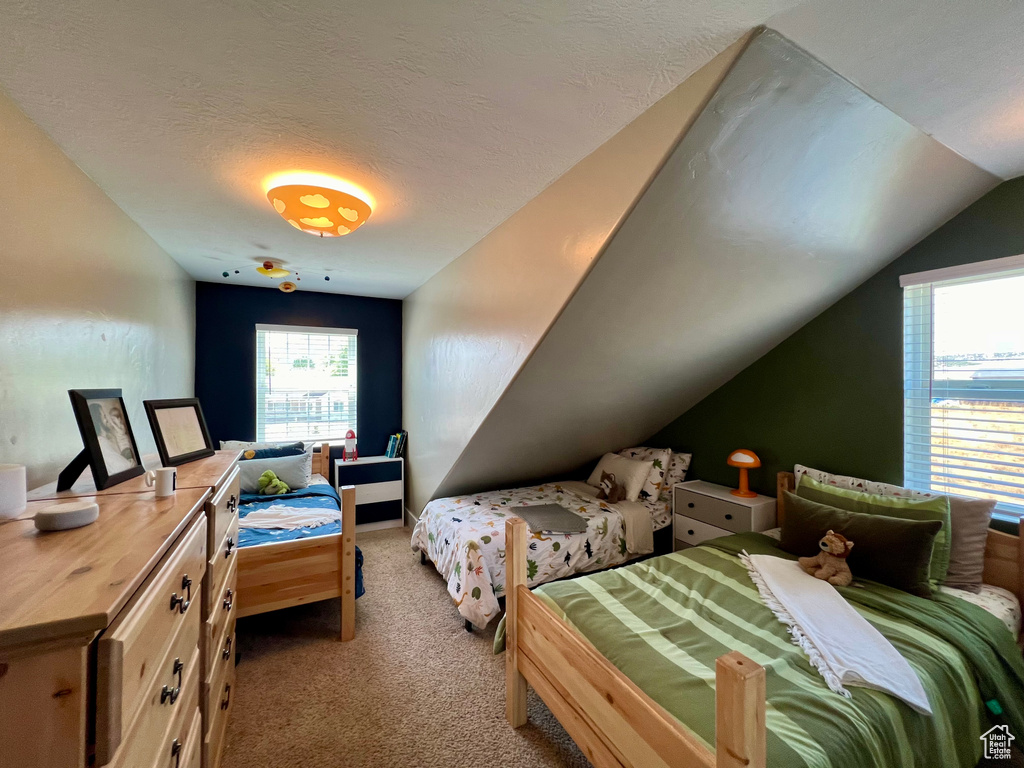 Carpeted bedroom featuring a textured ceiling and vaulted ceiling